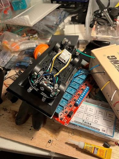 Underside of the model car's display base with a red multi-channel relay board and wiring